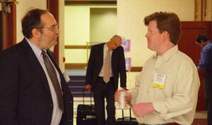 Dave and John facing each other talking in the hall